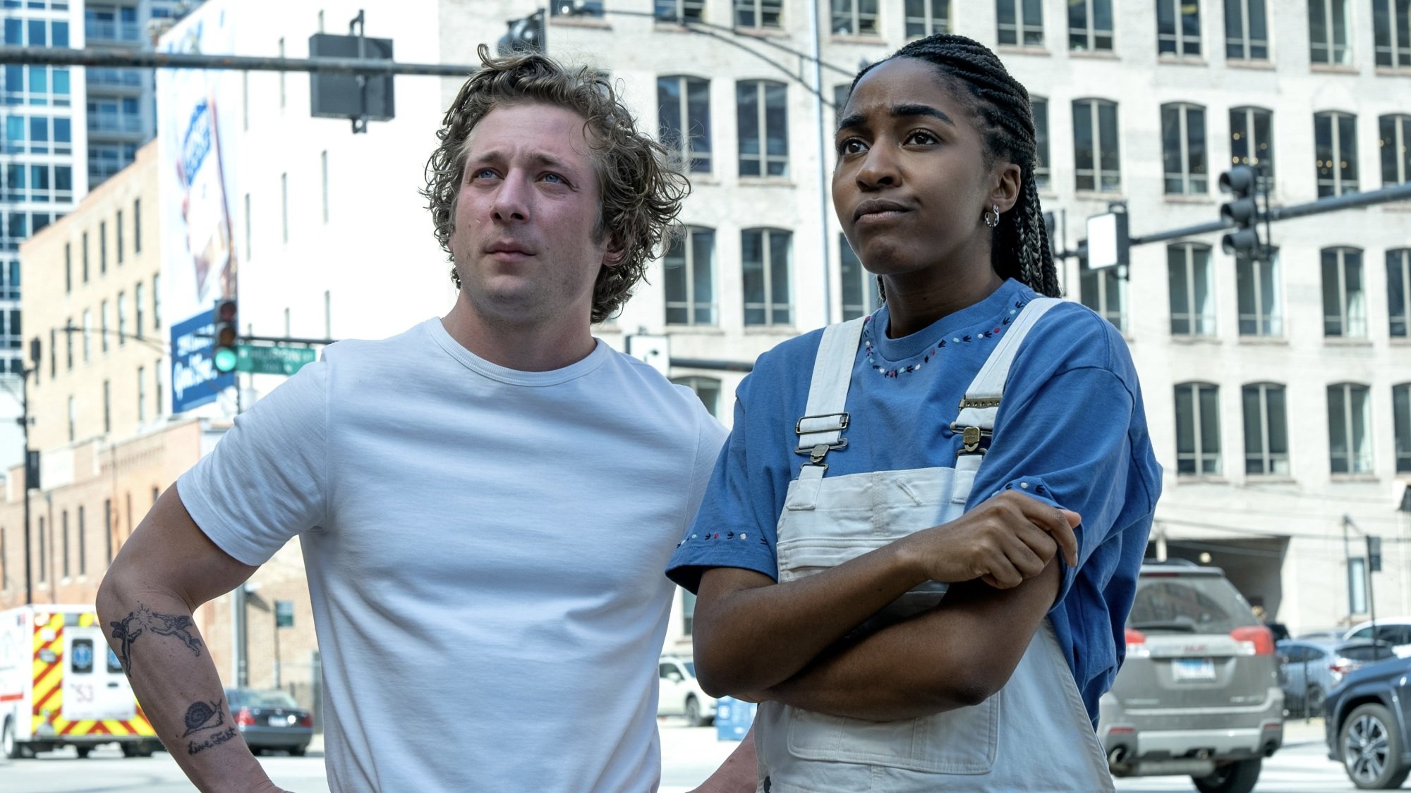 A man in a white T-shirt and a woman in a white chef's apron stand on a Chicago street.