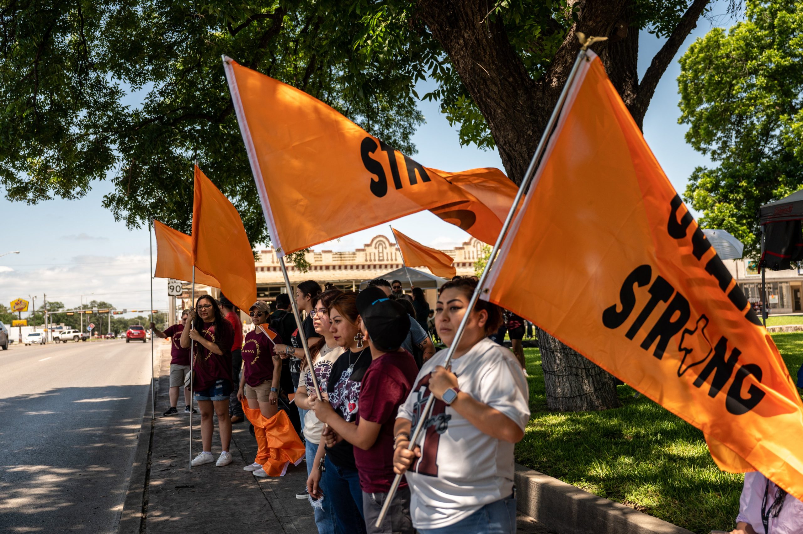 Community members hold up orange flags to remember the victims of the Robb Elementary shooting on Wednesday, May 24, 2023 in Uvalde, TX