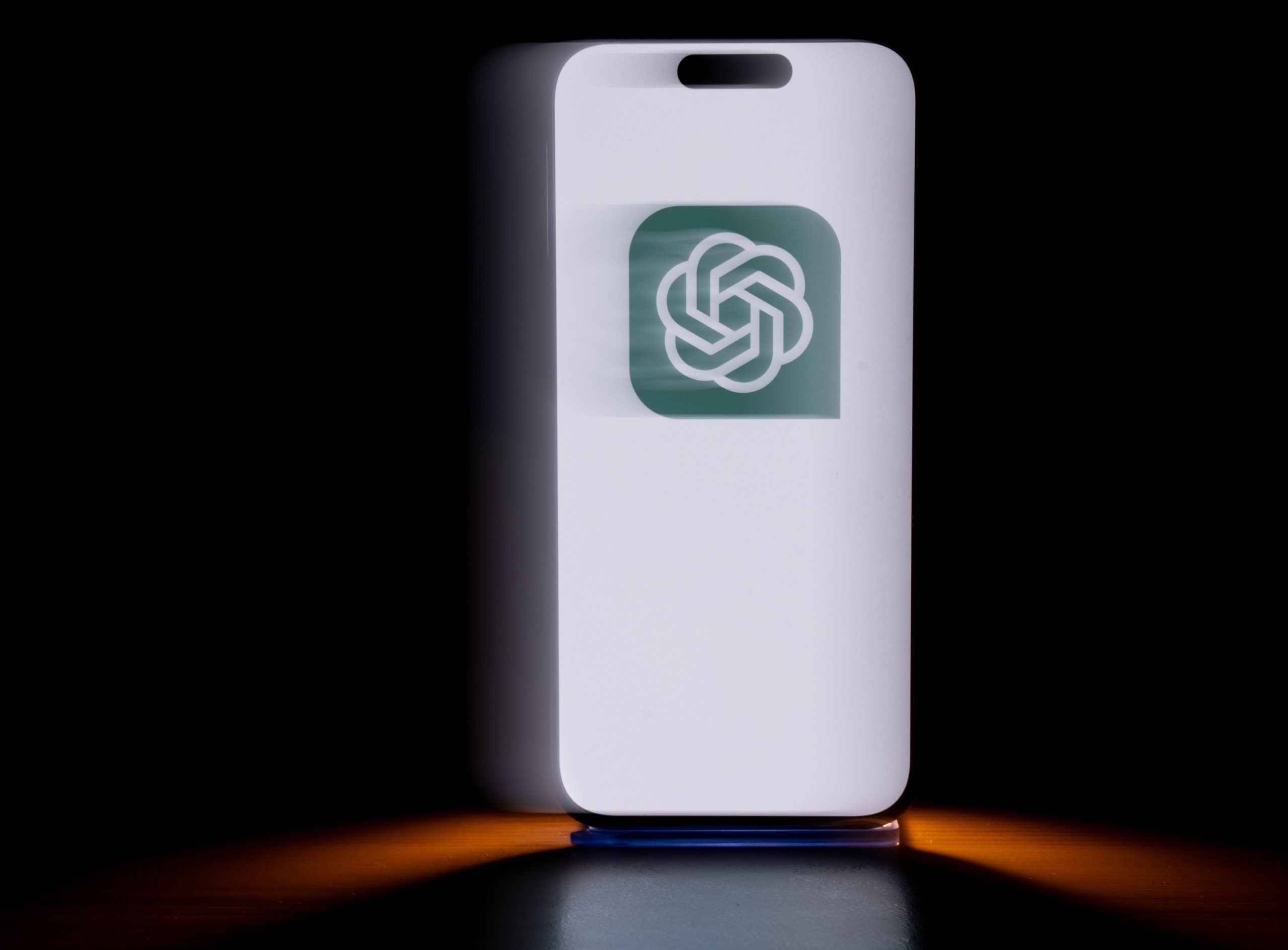 A phone displays a green OpenAI logo.