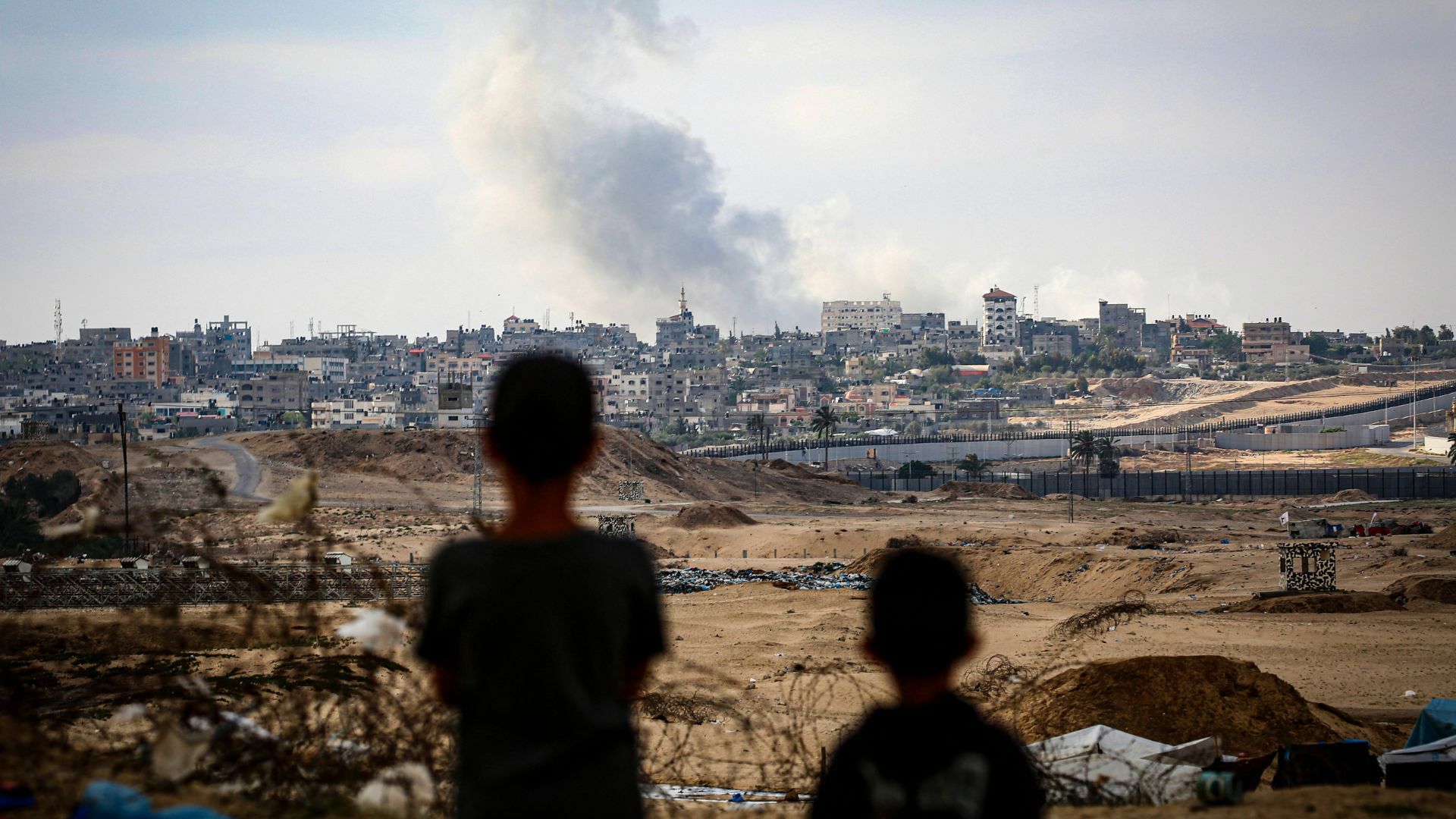 Boys watch smoke billowing during Israeli strikes east of Rafah in the southern Gaza Strip.