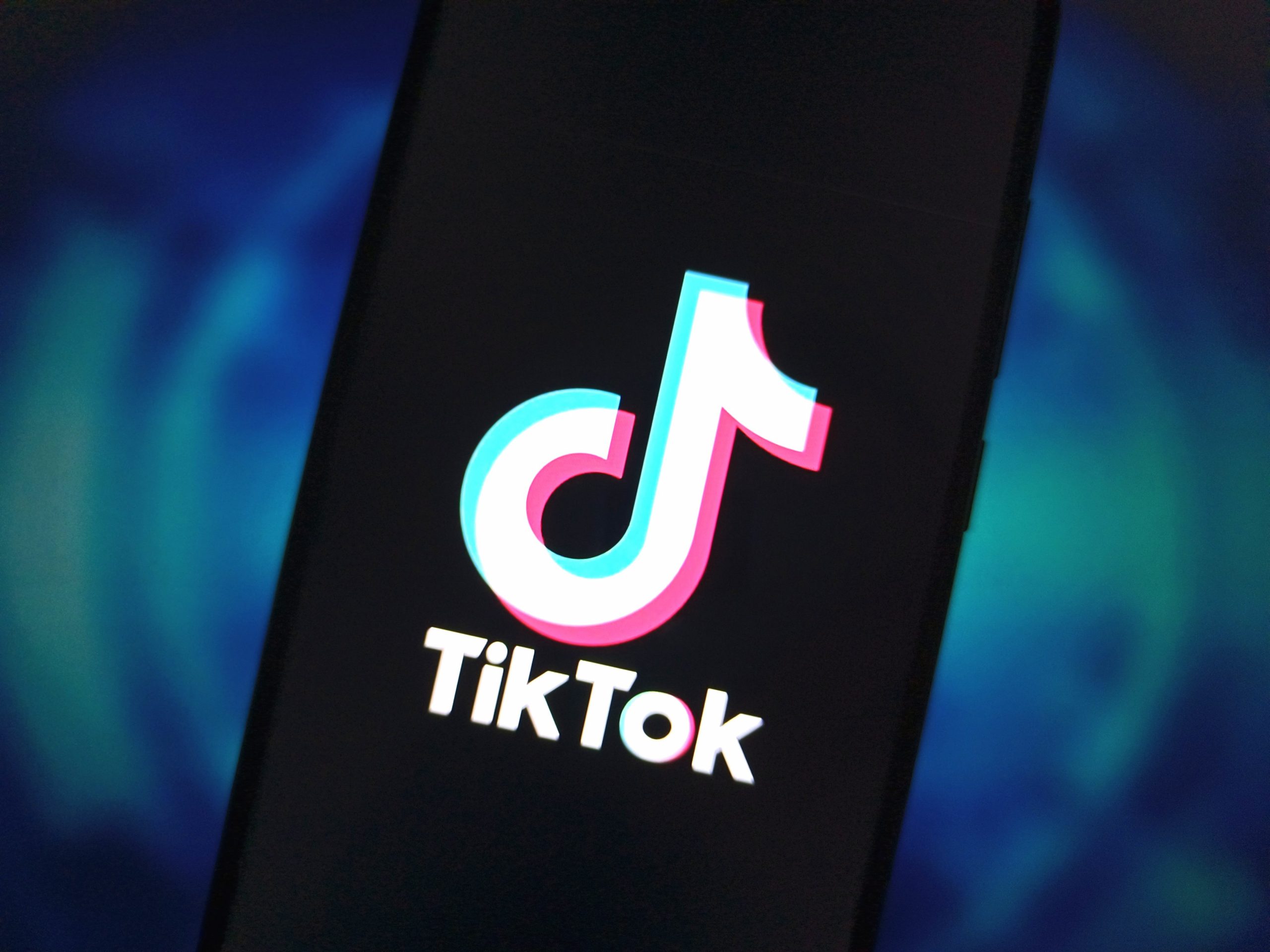 A phone screen displaying the TikTok logo in front of a blue backdrop. 