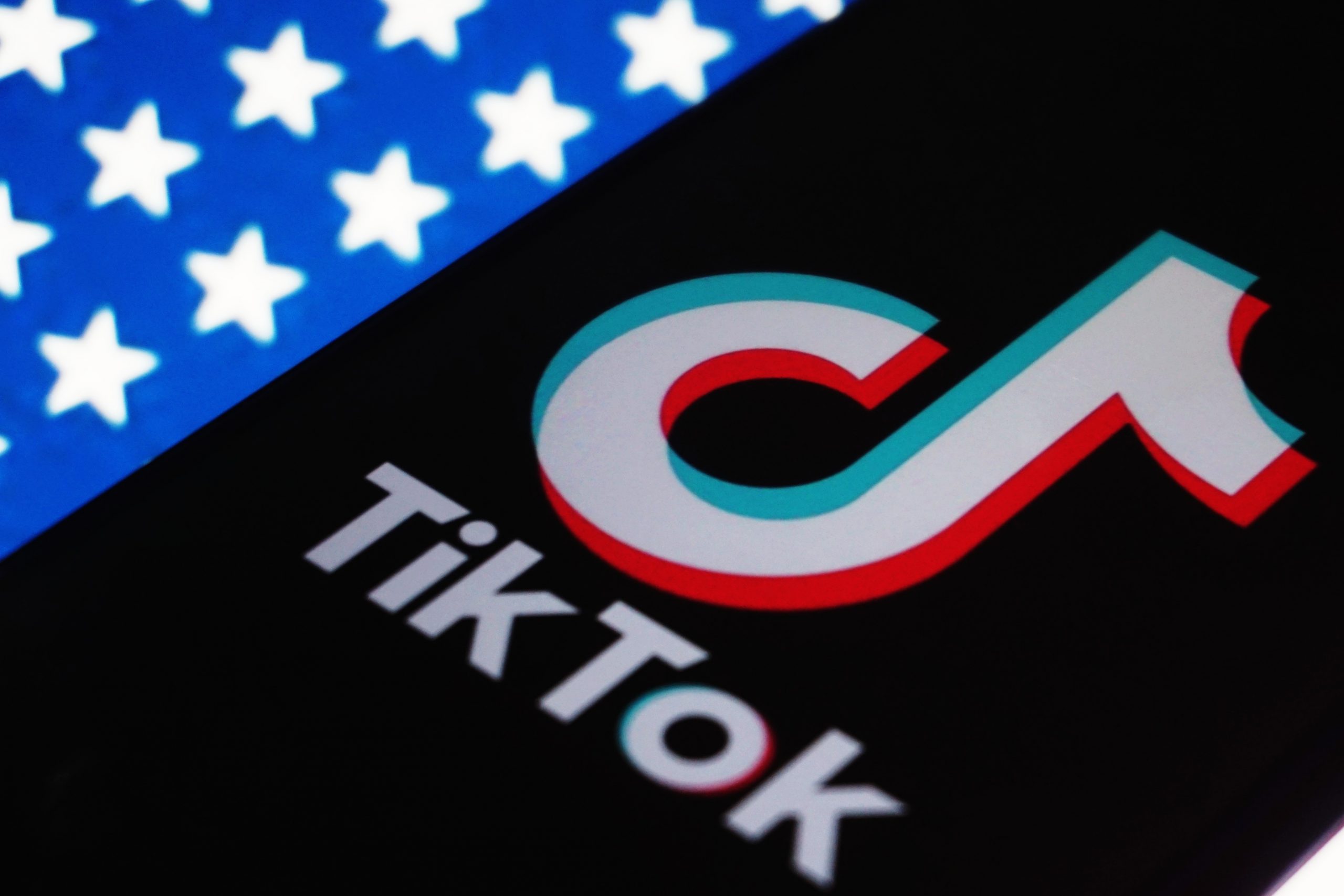 A phone displaying the TikTok logo on an American flag backdrop.