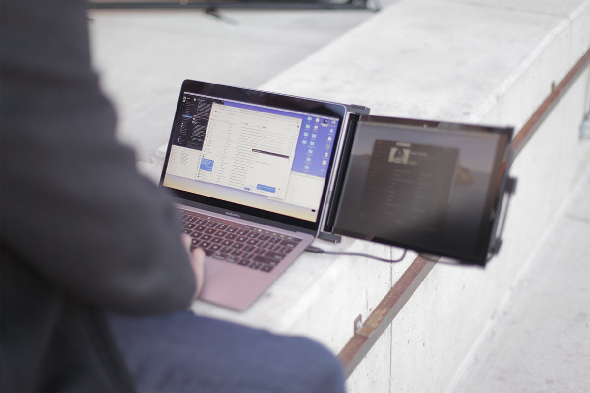 Man working on laptop with clip-on external monitor