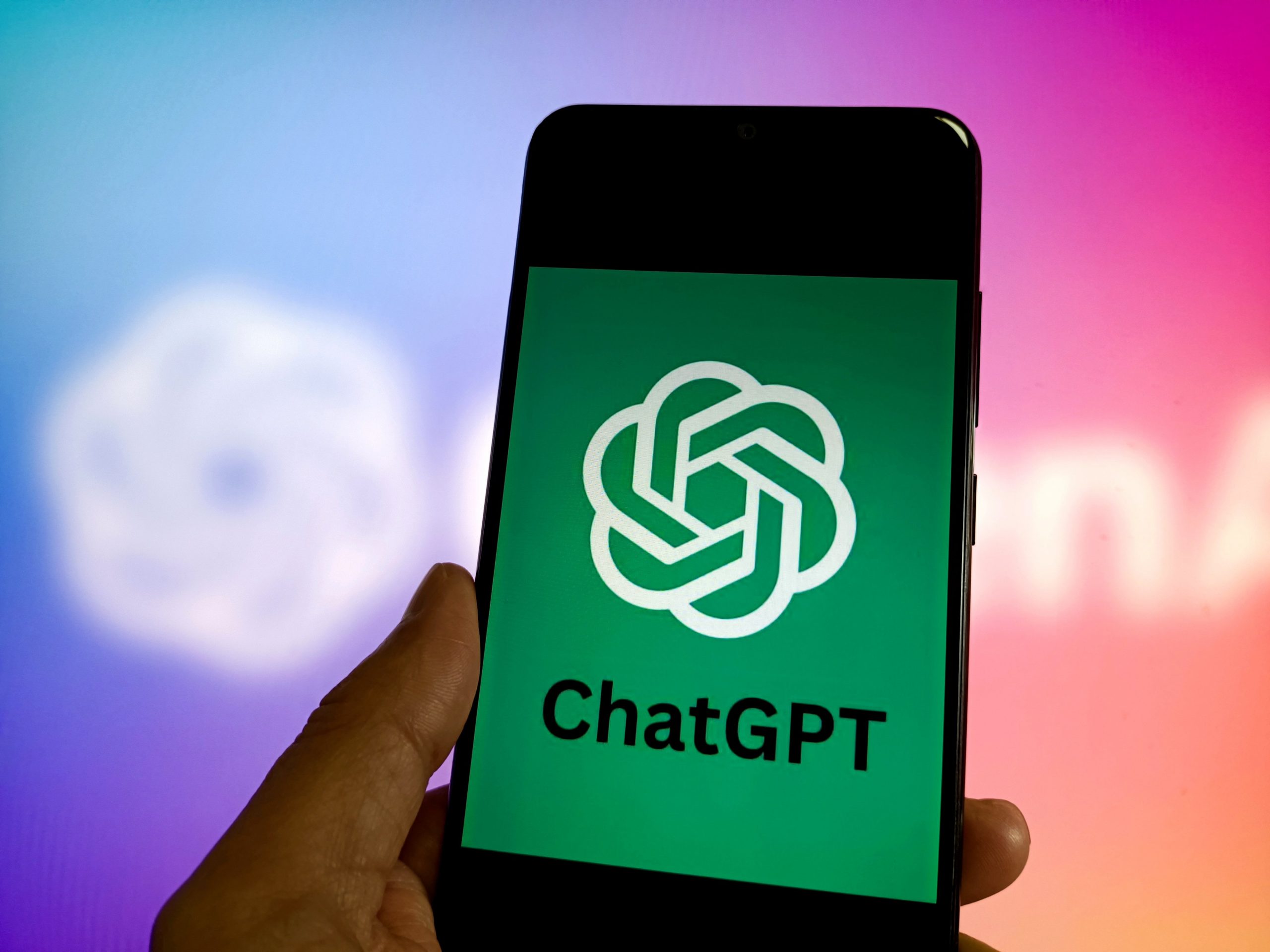 A hand holds a phone with the ChatGPT logo on the screen.