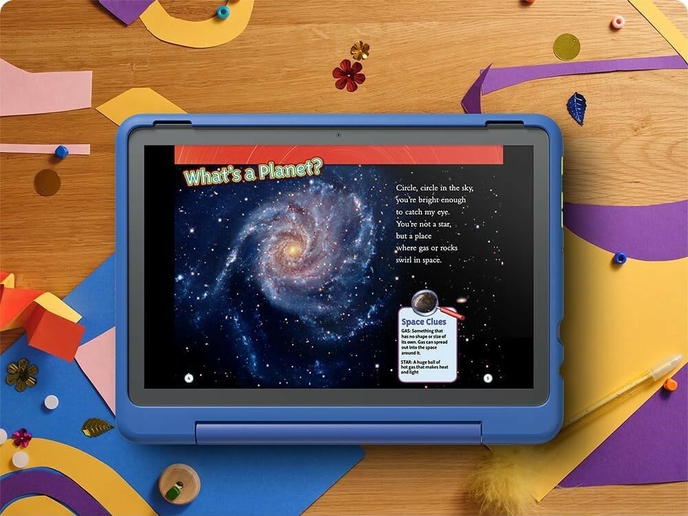 an amazon tablet for kids sits on a table with colorful shapes around it. the tablet displays a page of a book explaining what a planet is