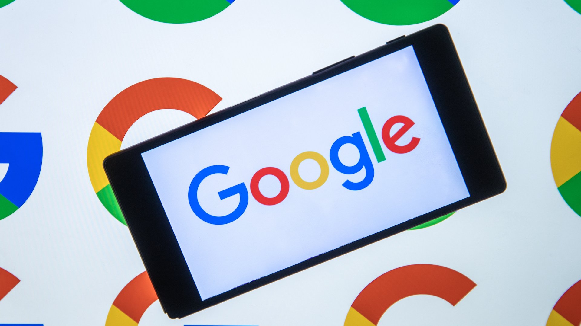  the logo of Google is displayed on the mobile phone screen in front of the logo of Google displaying on the screen
