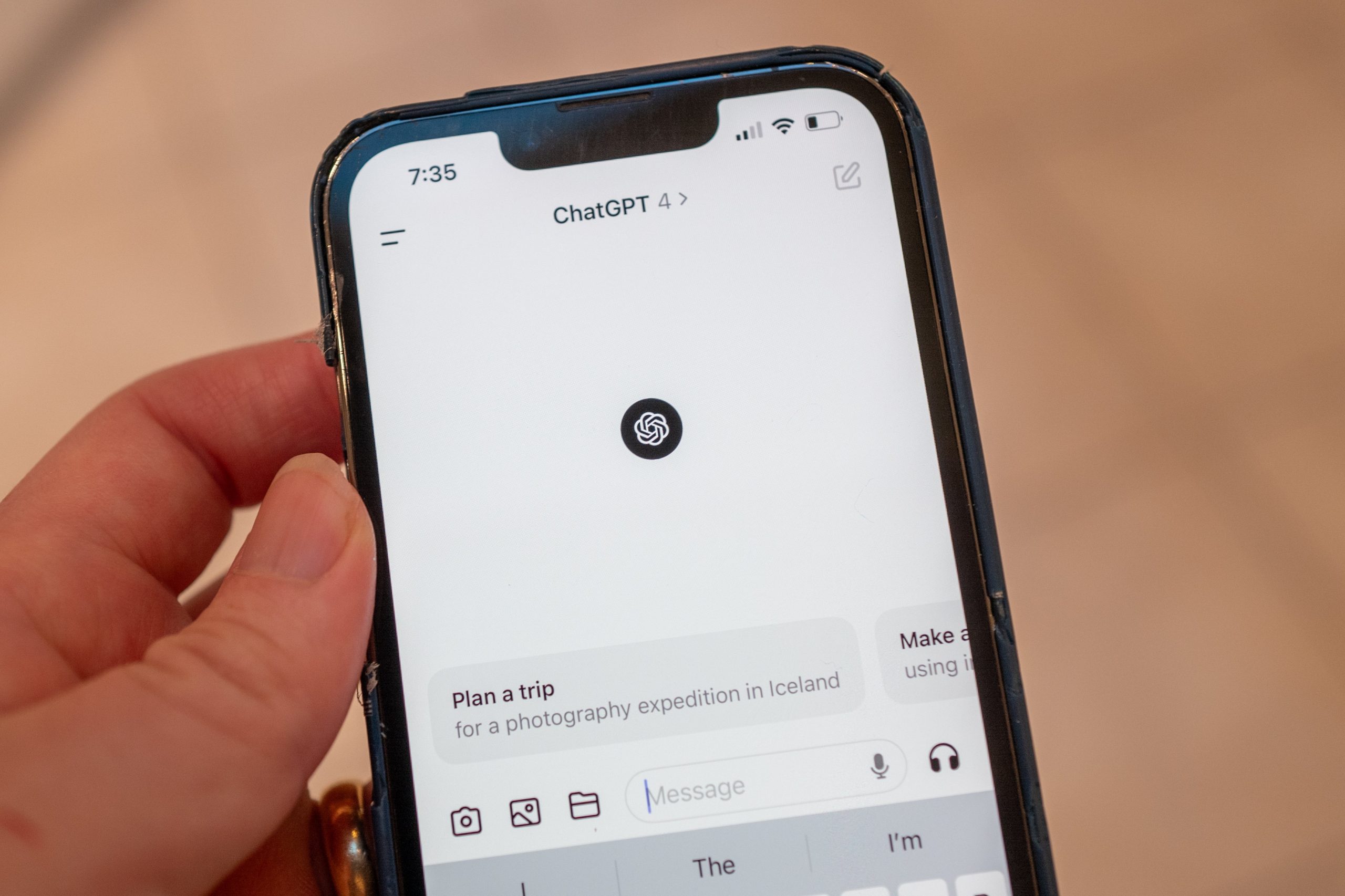 A person's hand holds an iPhone with the OpenaAI ChatGPT app running GPT-4 visible