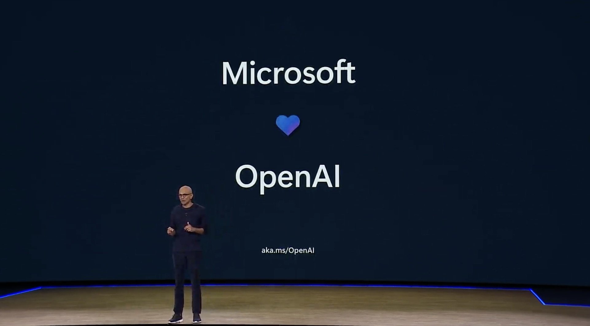 Microsoft CEO Satya Nadella in front of a screen that says Microsoft with a heart below and OpenAI