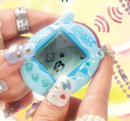 A white hand holds a Tamagotchi Connection in blue