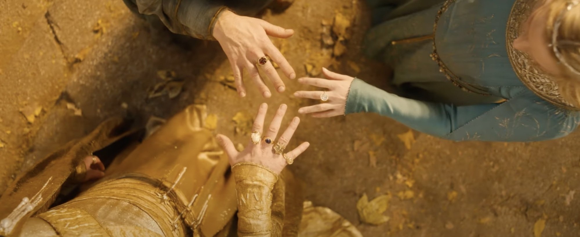 Three pale hands wearing rings.