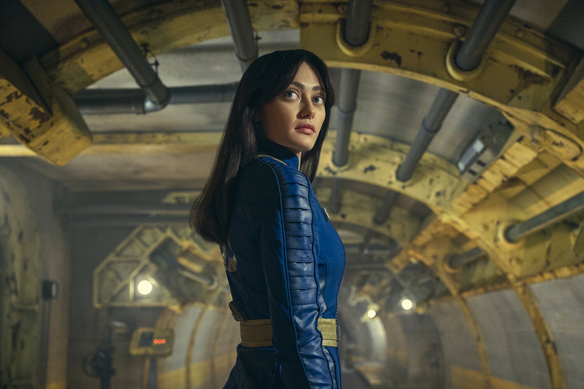 A woman in a blue futuristic-looking outfit looks behind her.