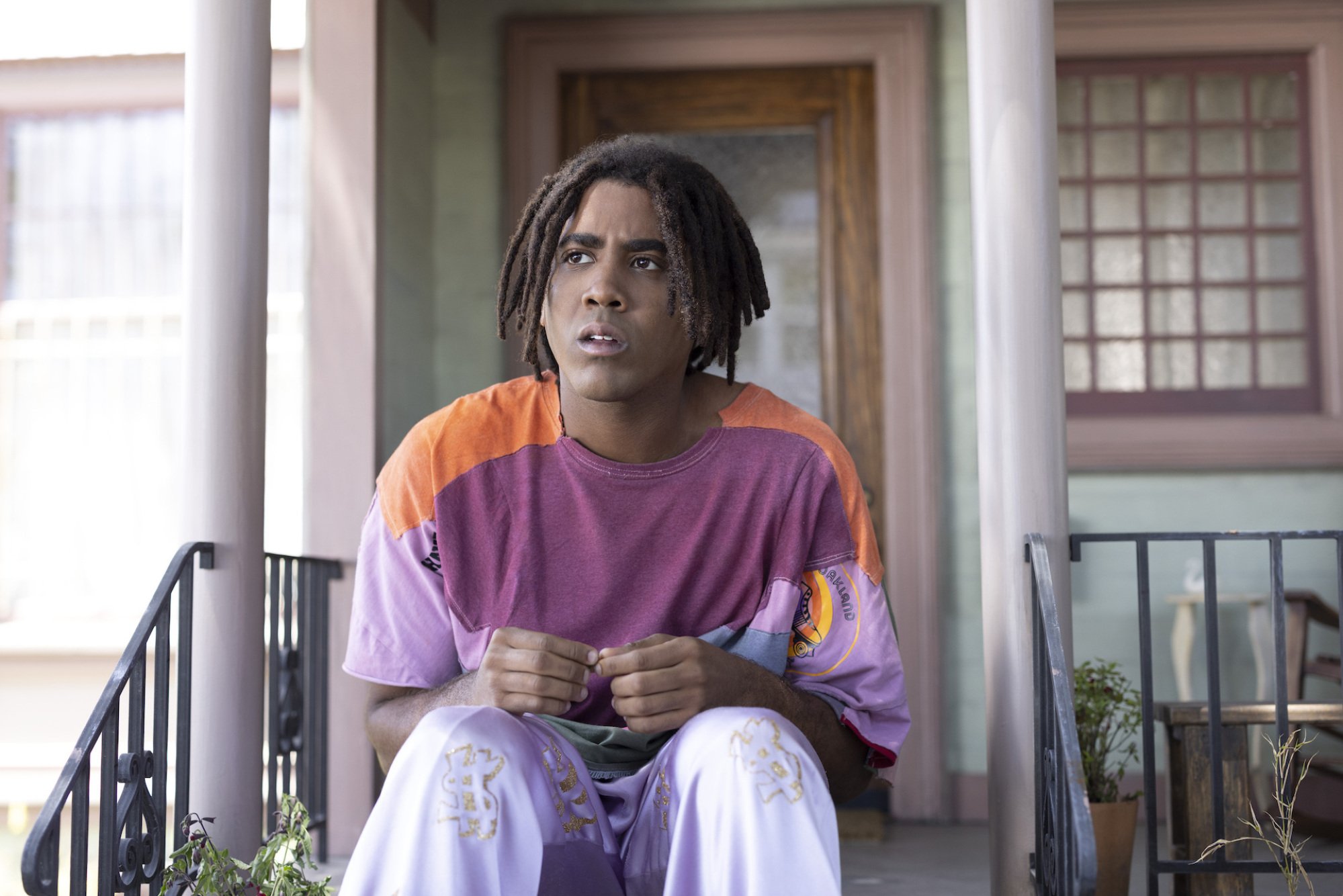 A 13-foot-tall Black man sits on a stoop.