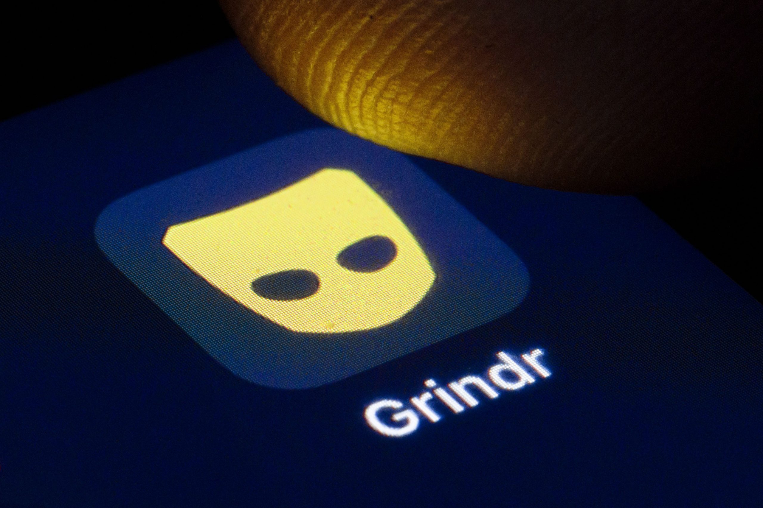 someone tapping grindr on a phone