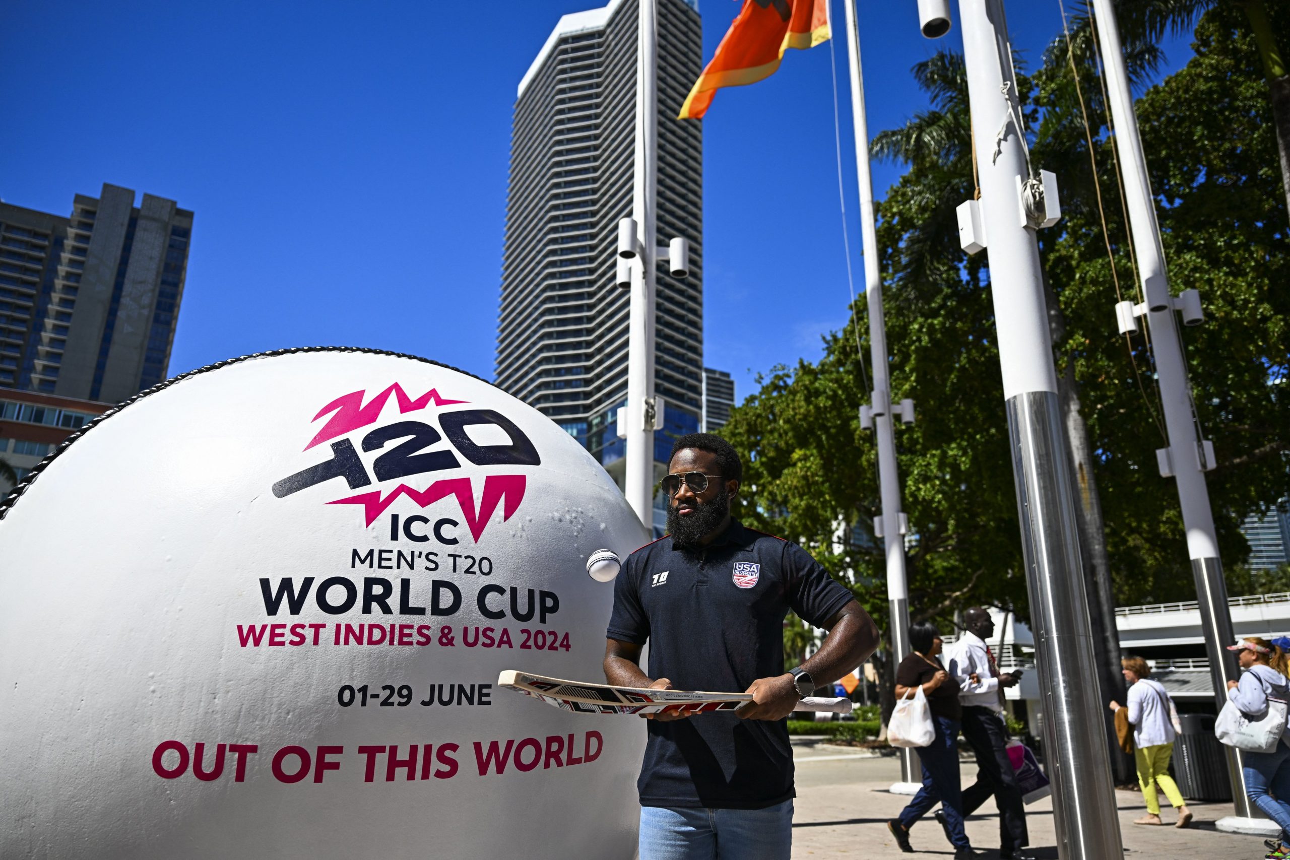 USA Cricket Vice-Captain Aaron Jones taps a ball with a bat next to a giant T20 marketing cricket ball