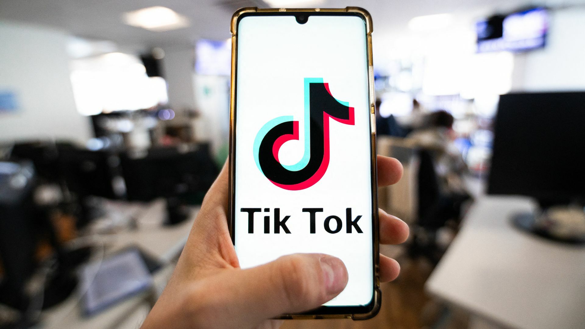 A man holding a smartphone displaying the logo of TikTok.