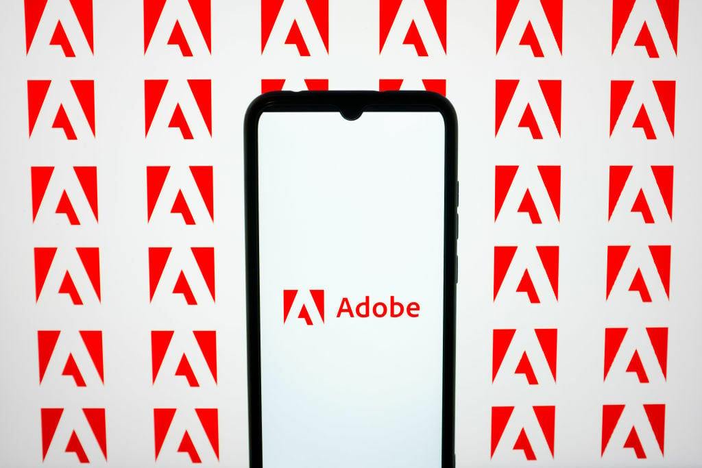 adobe logo on a smartphone against a background of adobe icons