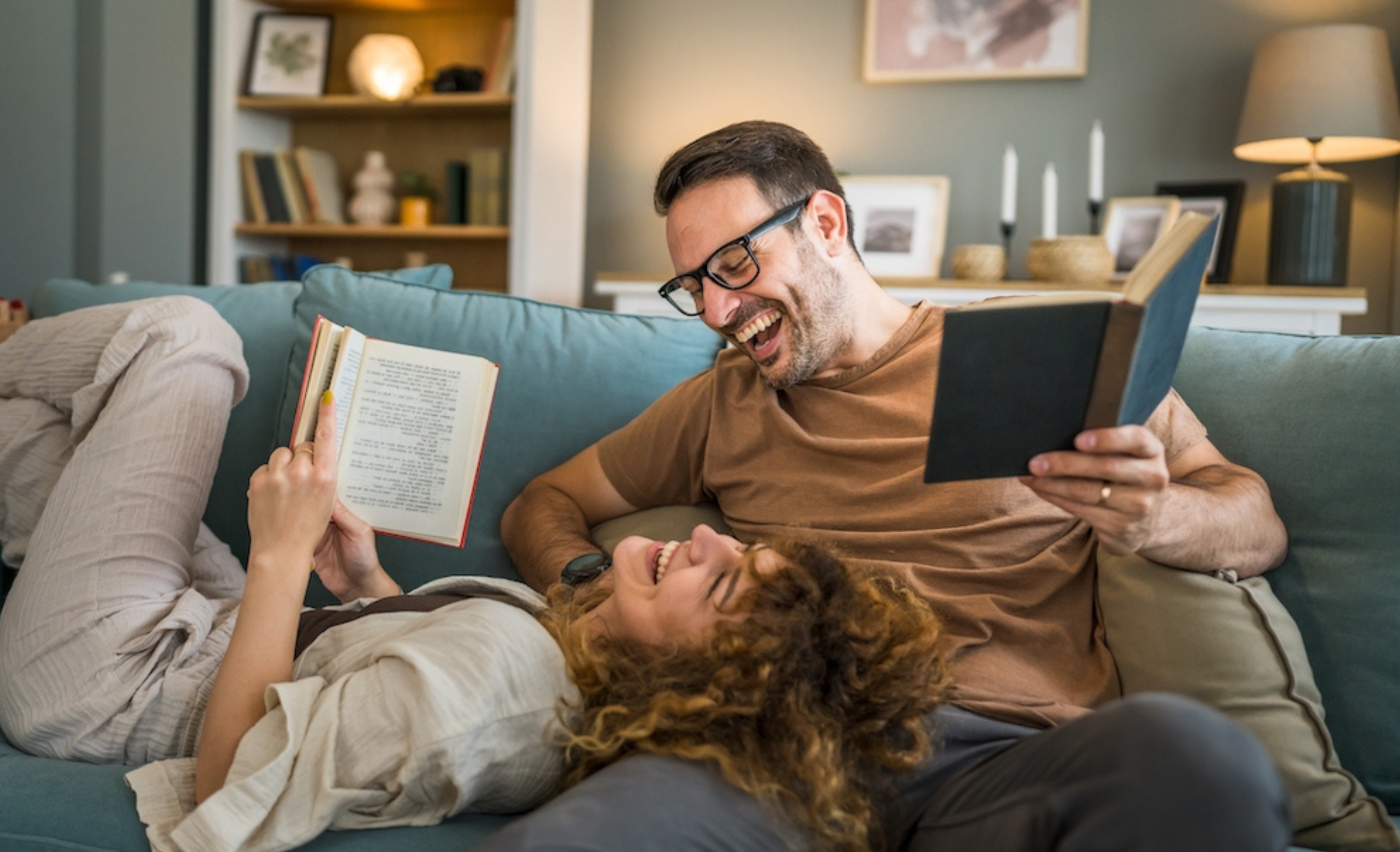 Adult couple man and woman Caucasian husband and wife in a relationship real book hold books on the sofa bed at home in the apartment reading leisure bonding family concept real people copy space