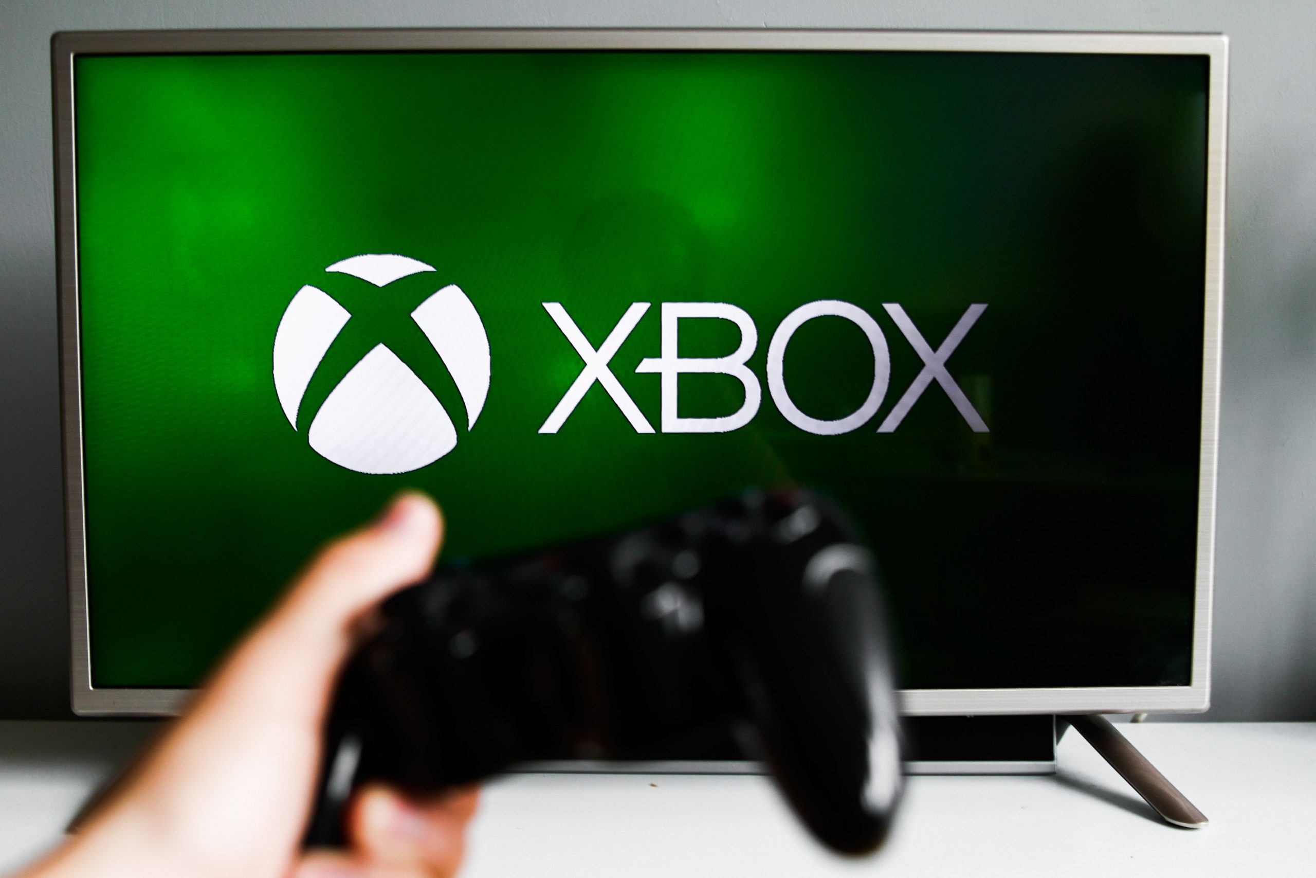 xbox logo on tv with hand holding controller in foreground