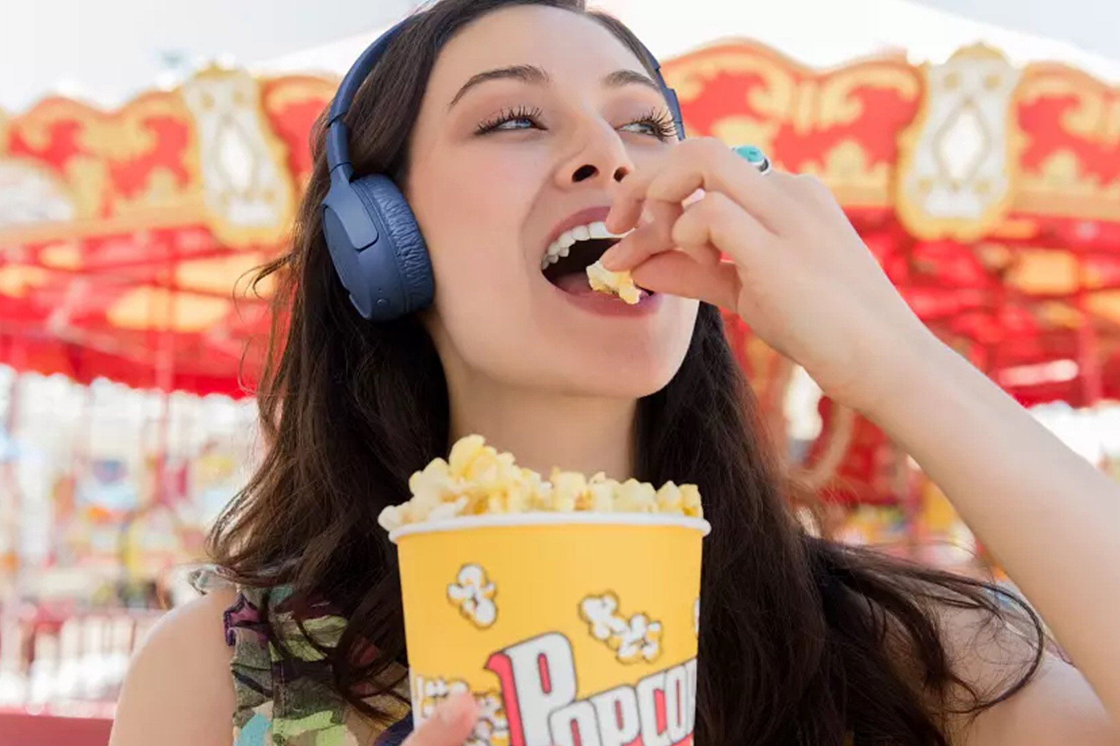 Woman eating popcorn and listening to music with JBL headphones