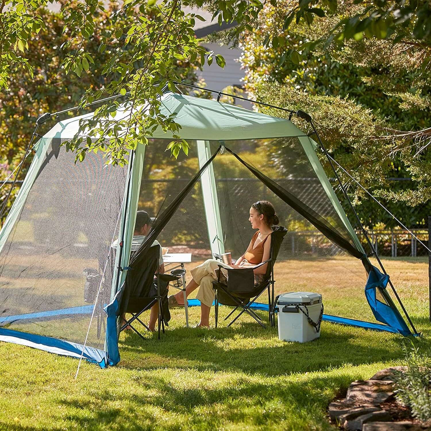 People sit under the Coleman Skylodge Screened Canopy Tent