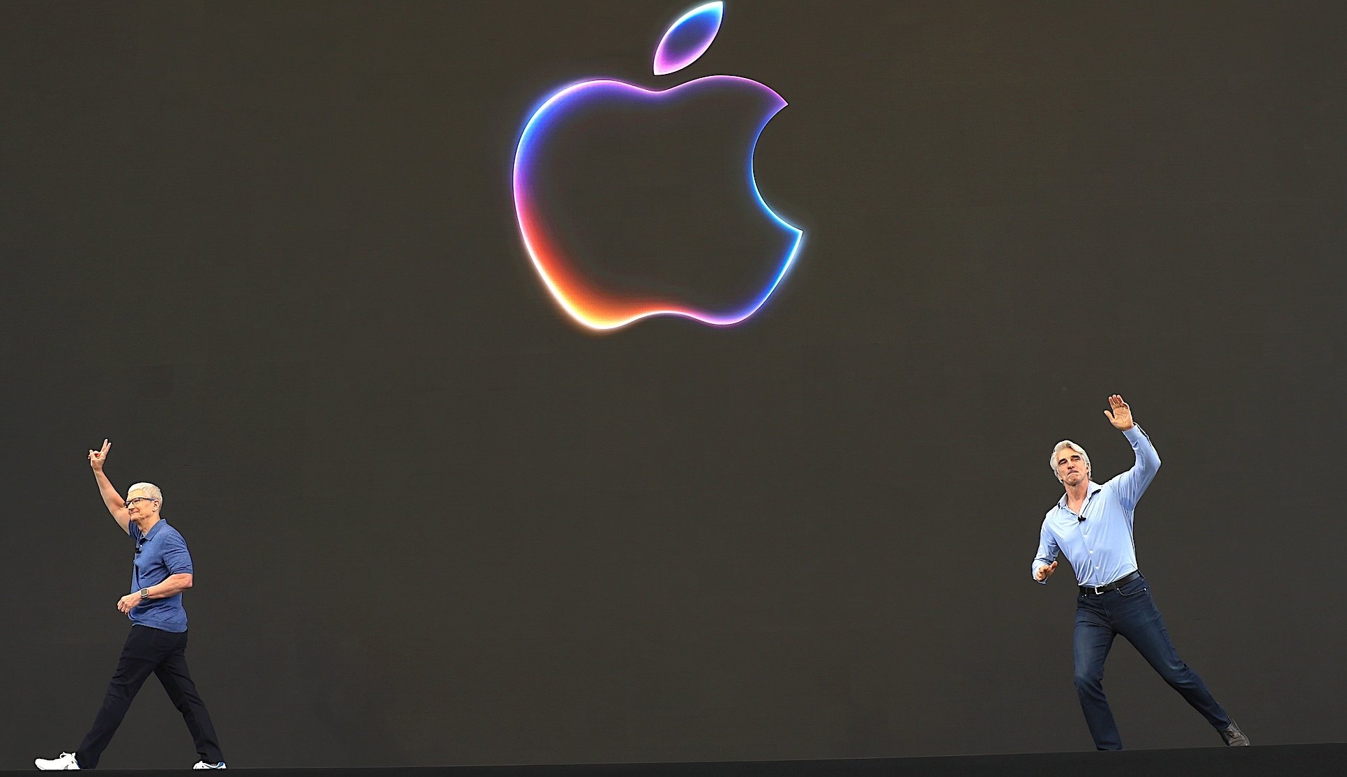 Tim Cook leaves a stage with a large Apple logo as Craig Federighi arrives from the other side