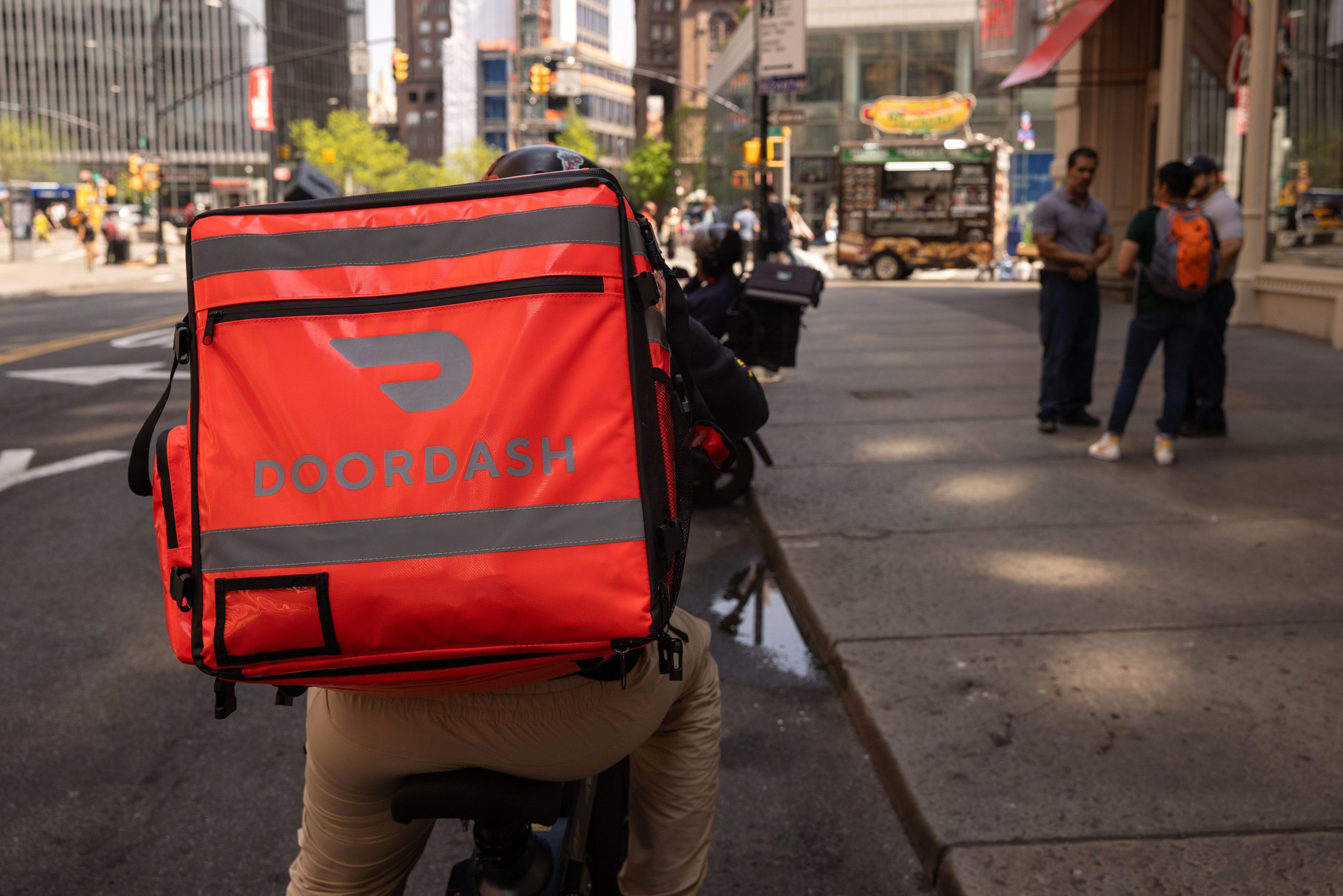 Delivery driver on bike wearing Doordash backpack riding through city