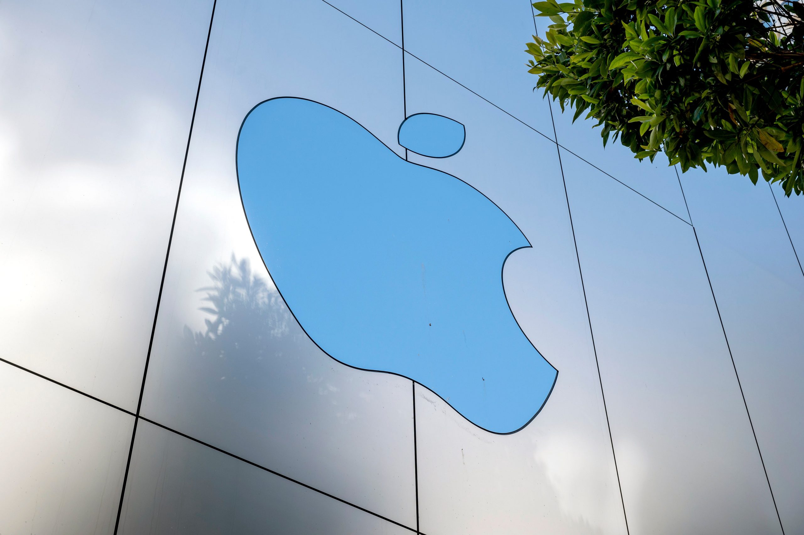 A large Apple logo on the side of a reflective building. 