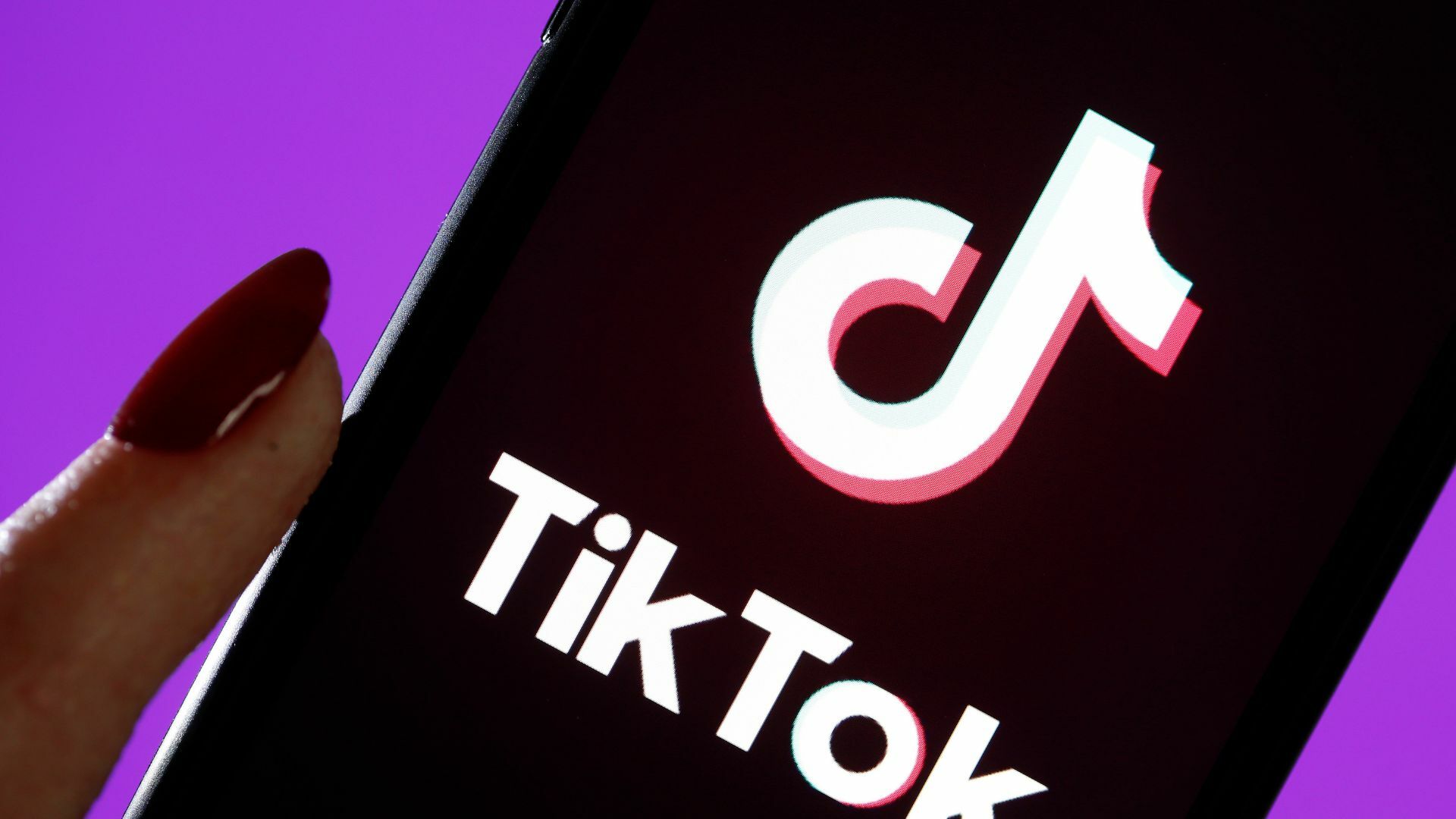 A hand holding a phone displaying the TikTok logo.