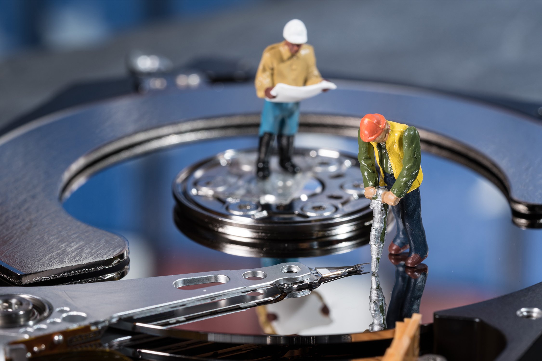 miniature worker figurines on hard drive