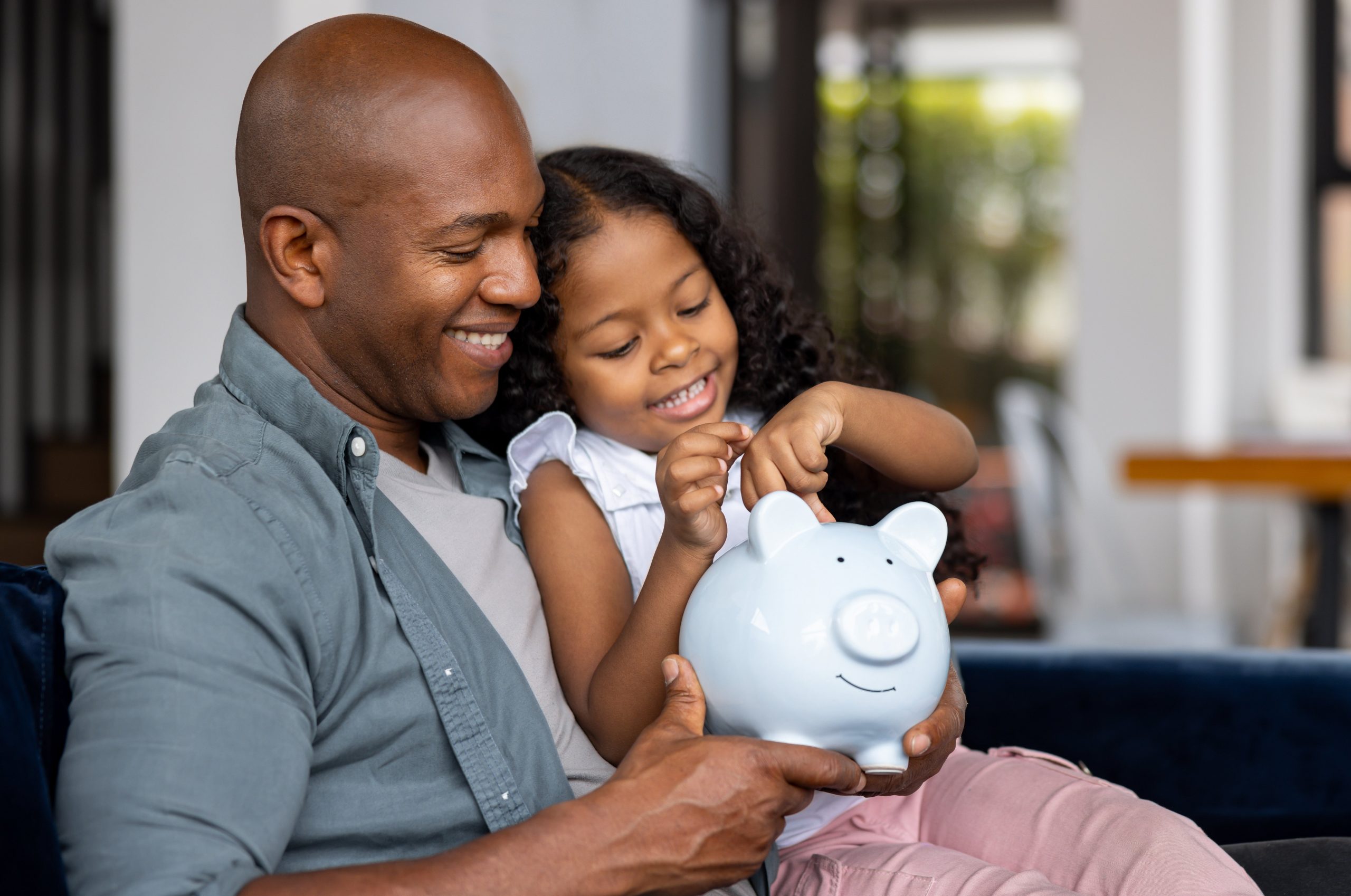 Father and daughter putting money in a piggy bank