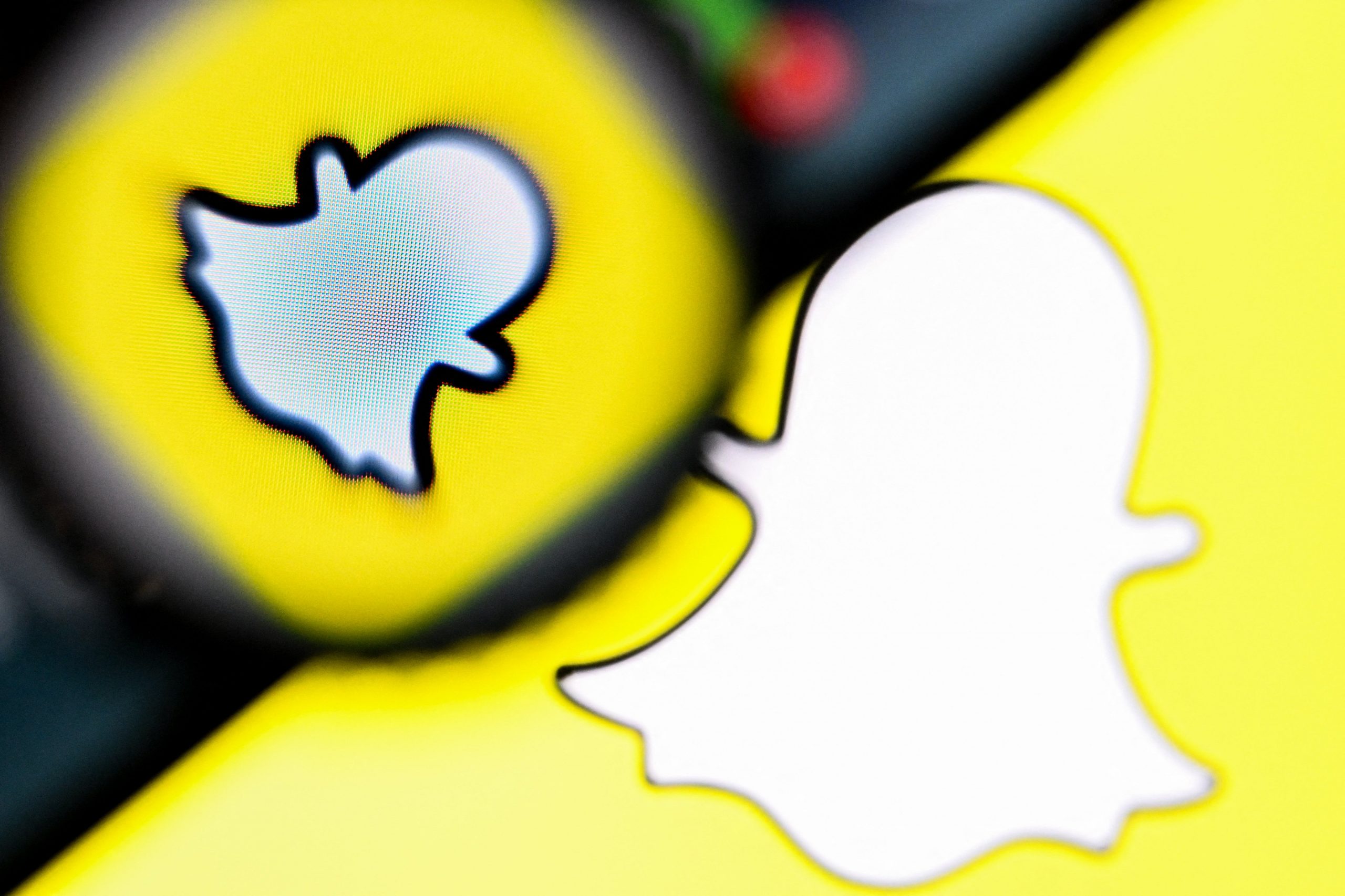 A snapchat logo with a magnifying glass and a phone hovering over it. 