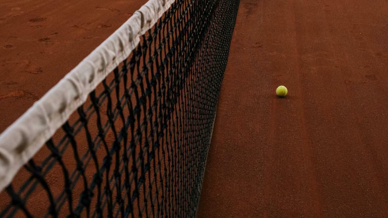 Tennis net and ball on a clay court