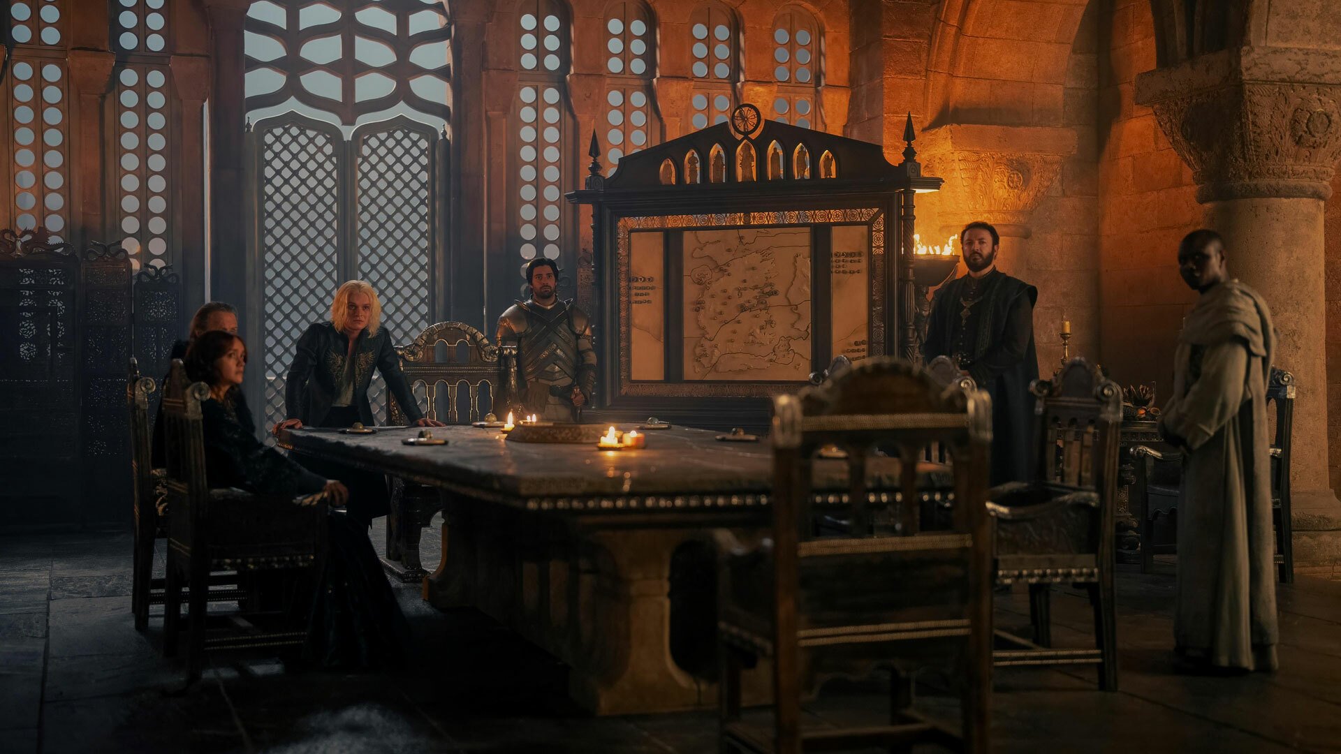 A group of people in medieval clothes sit and stand around a table.