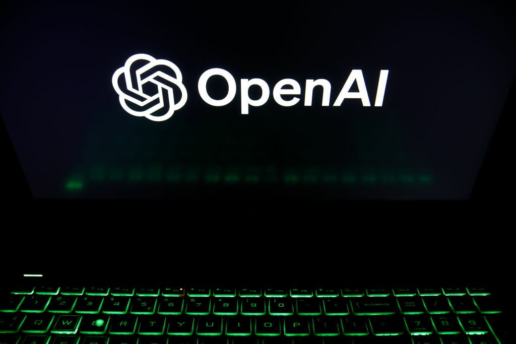 The OpenAI logo is being displayed on a laptop screen with a glowing green keyboard 