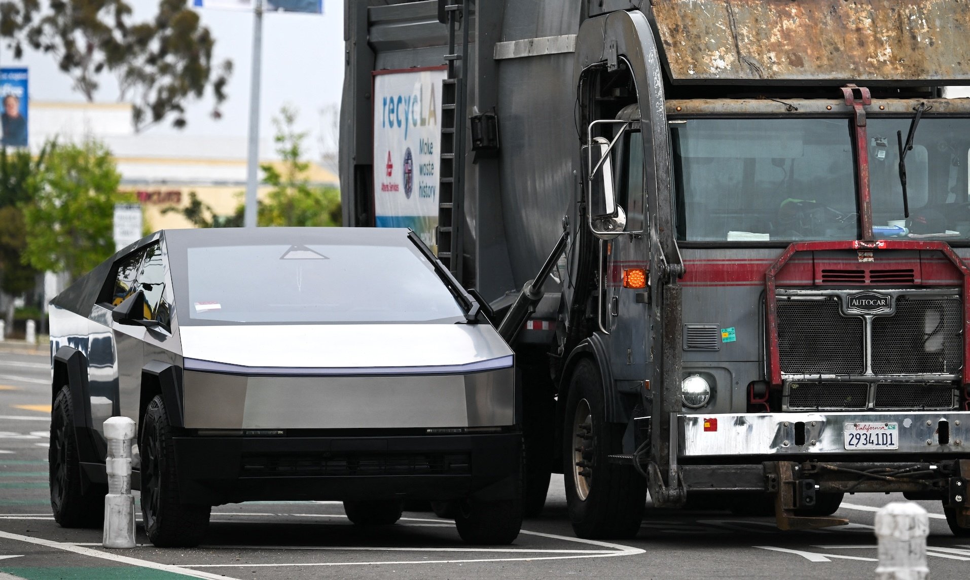 A Cybertruck parked next to a garbage truck