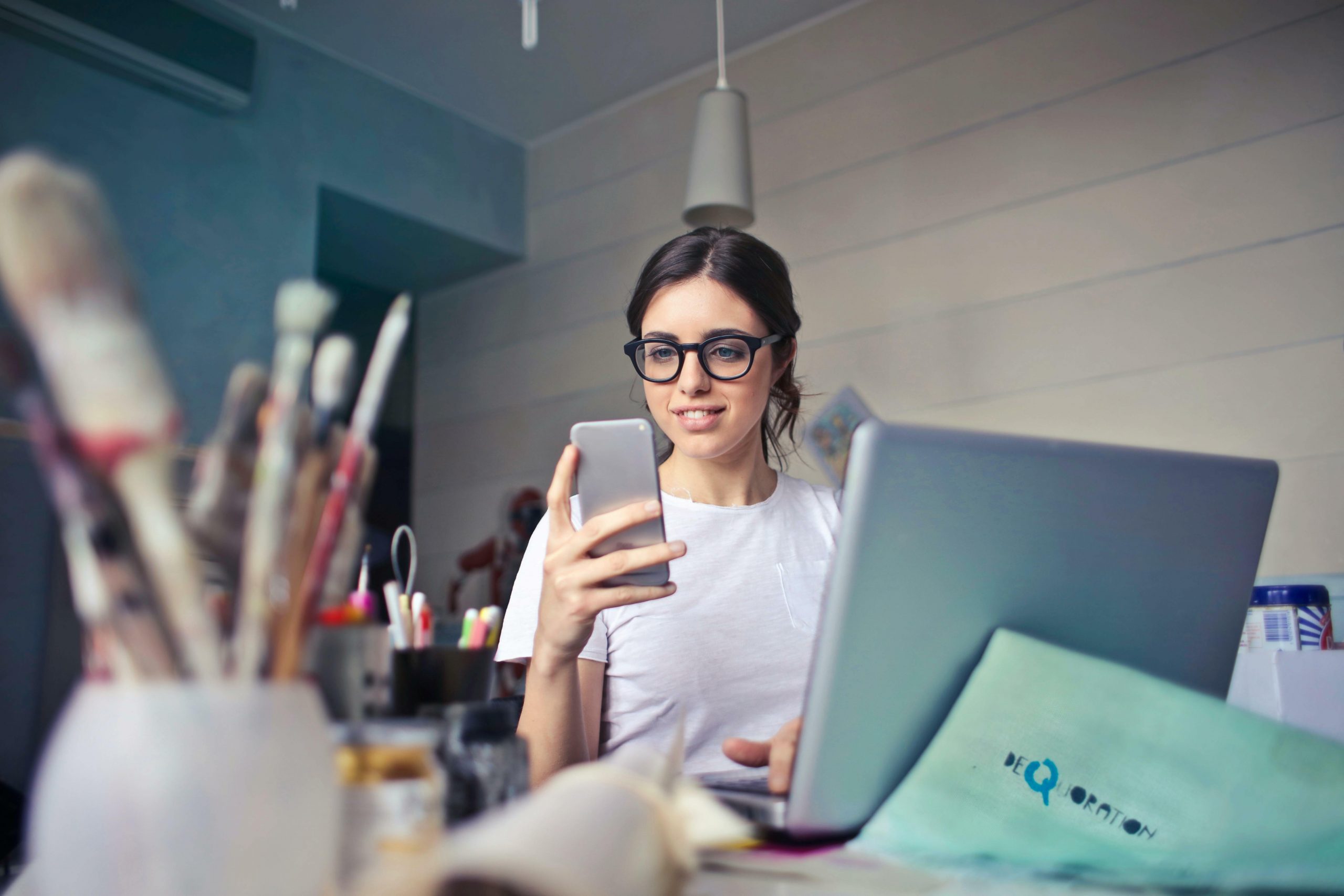 A woman looks at her phone at her workspace.