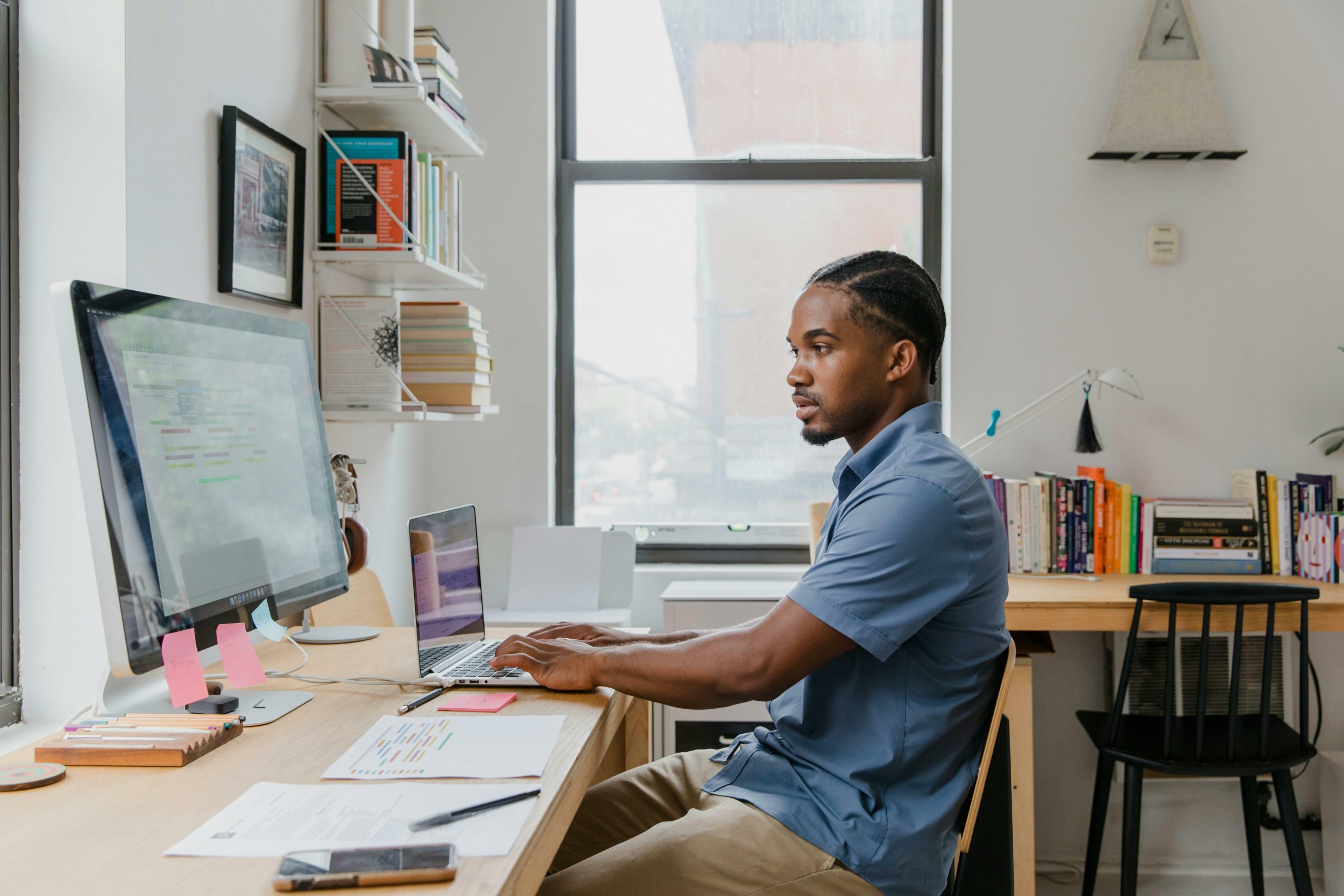 Black Man working at desk with computers in office