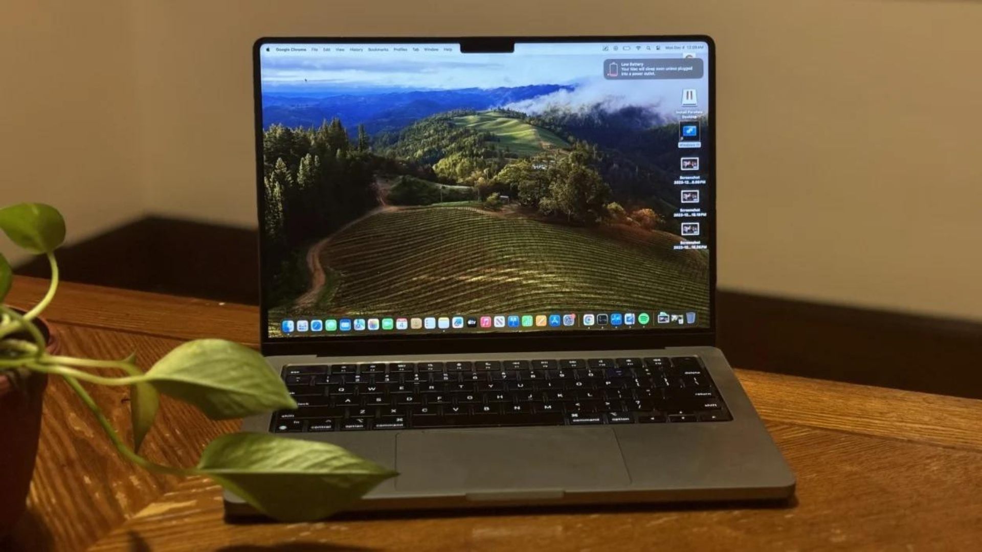 A 14-inch MacBook Pro sitting on a table next to a plant.