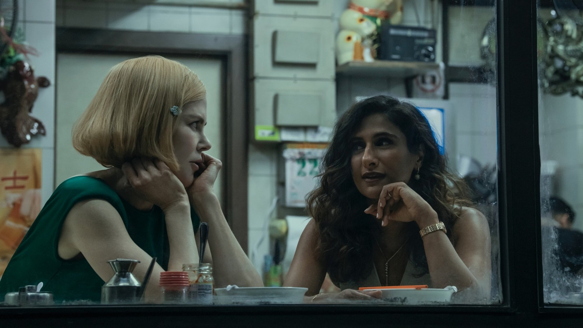 Two women eat at a window counter in a restaurant.