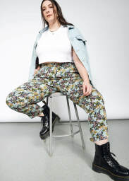 A person sitting on a bench wearing colorful Wildfang trousers.