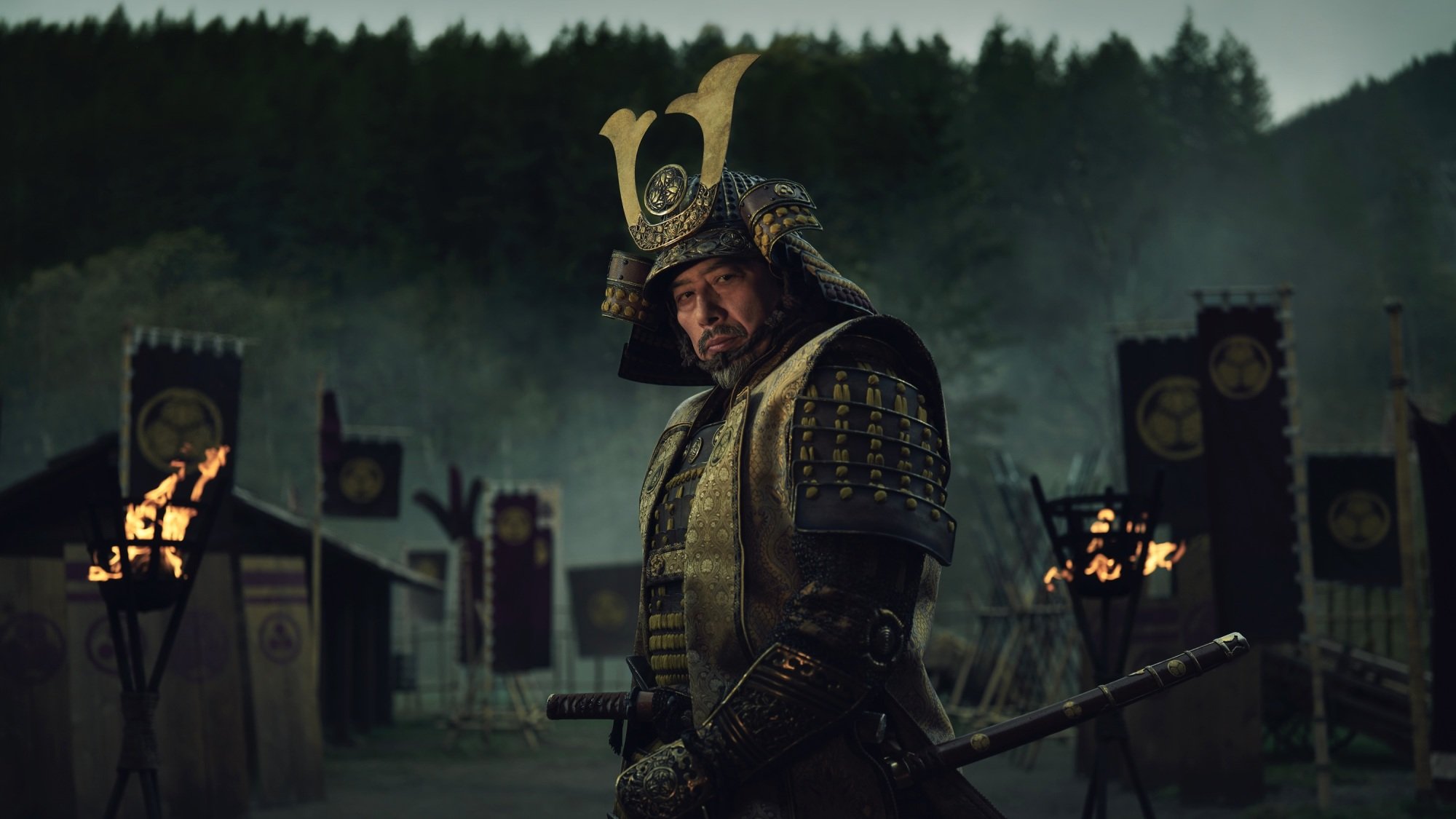 A man in samurai armor stands on a battlefield.