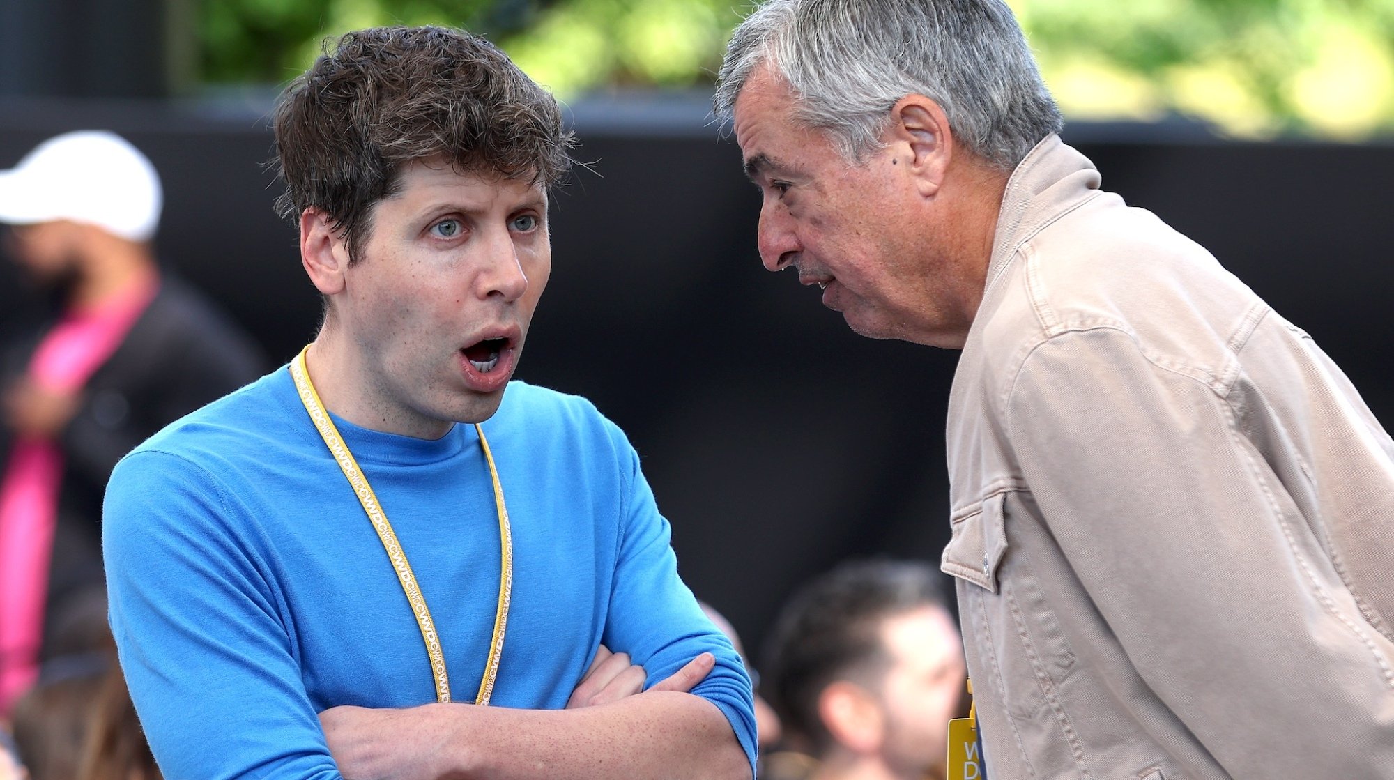 Sam Altman reacts, agape and arms folded, to an older man