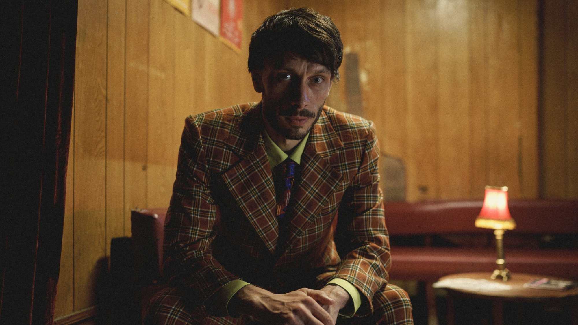 A man in a plaid suit sitting down.