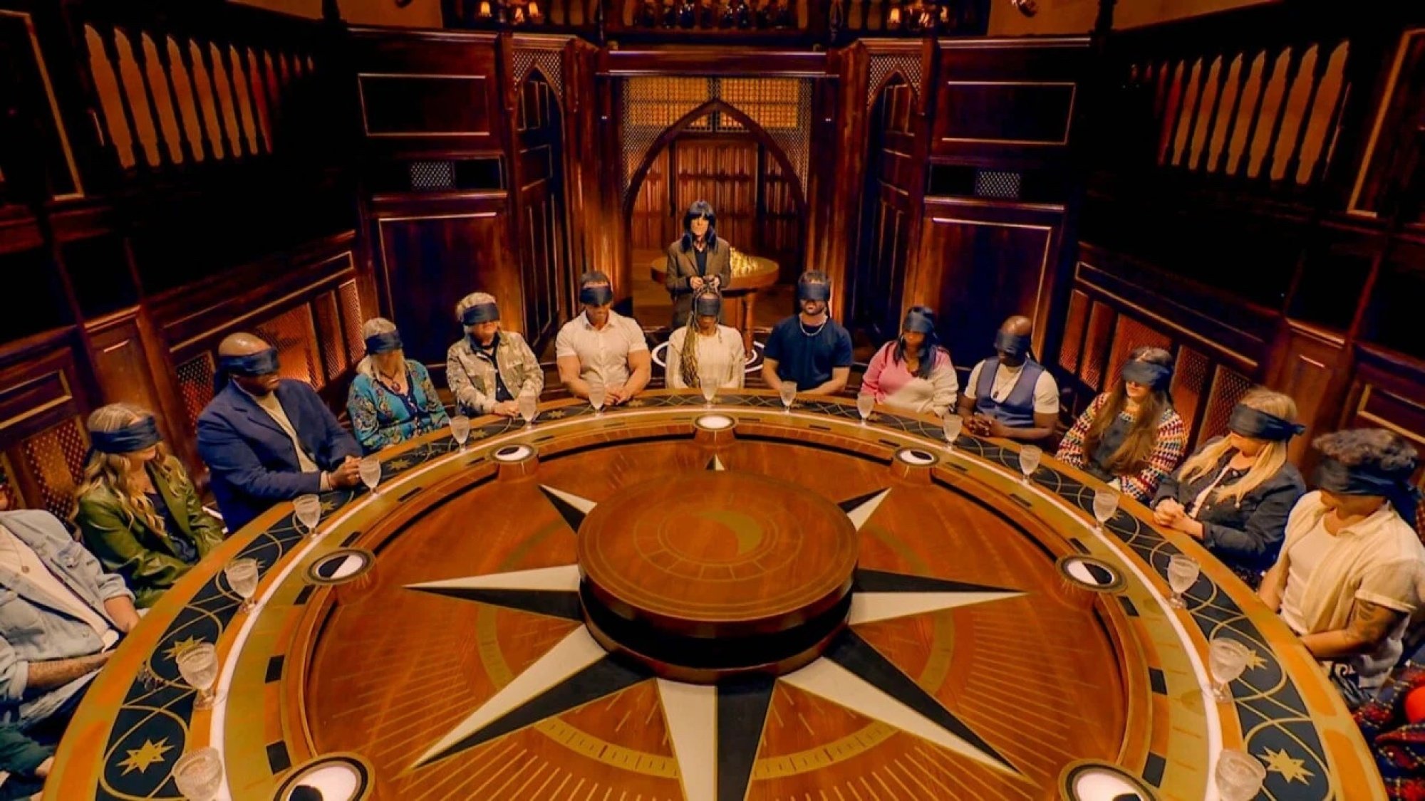 A group of blindfolded people sit around a large round table.