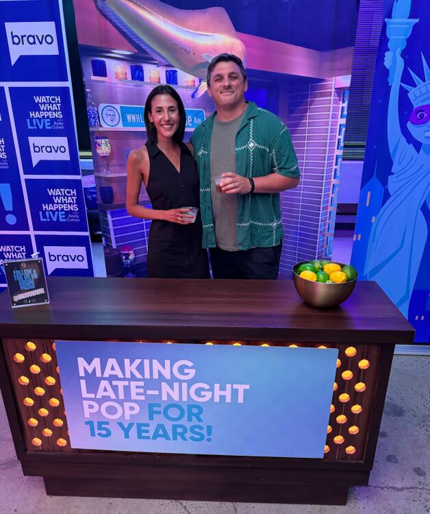 couple standing in front of faux wwhl desk