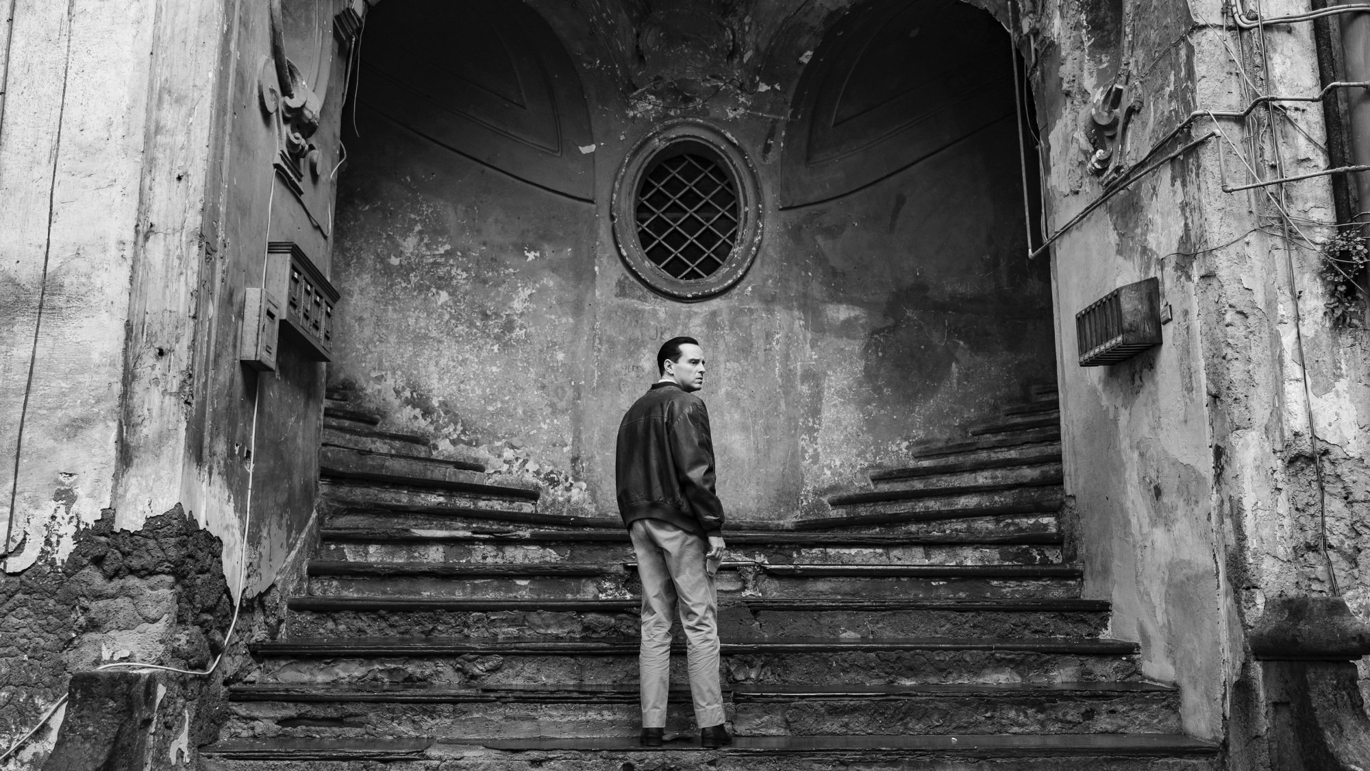 A man stands on a staircase leading to two different paths up.