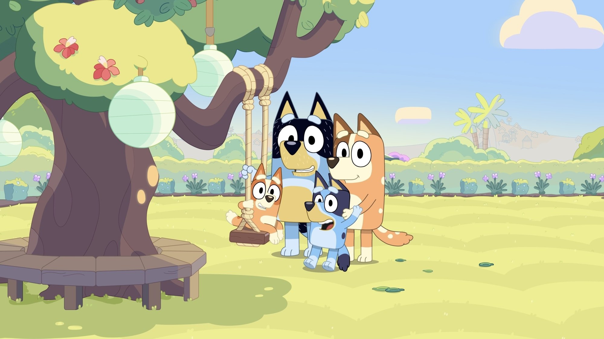 A family of cartoon dogs gather around a swing tied to a tree branch, with the smallest among them sitting on the swing.