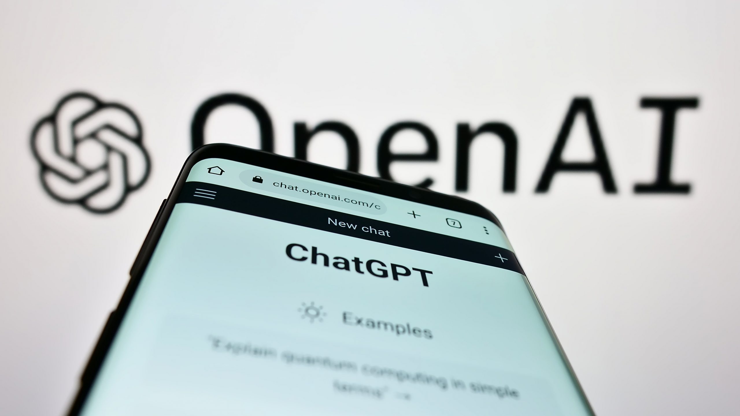 OpenAI logo with ChatGPT app on a phone