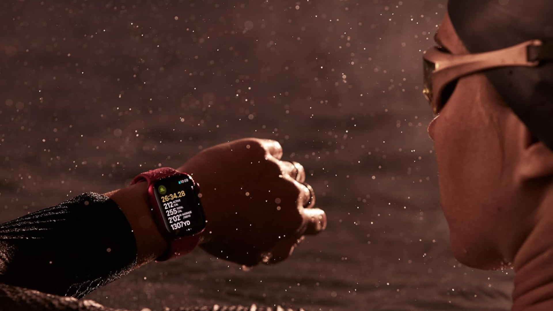 A person swimming in the water looking at an Apple Watch 9 on their wrist.