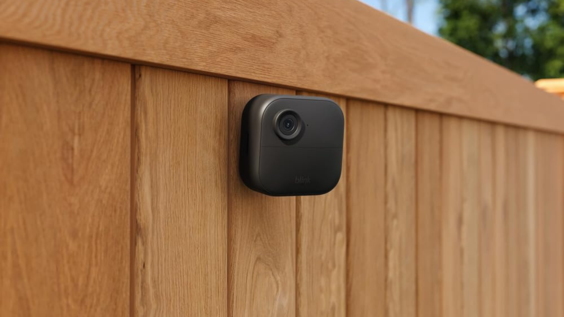 A Blink security camera on a wooden fence